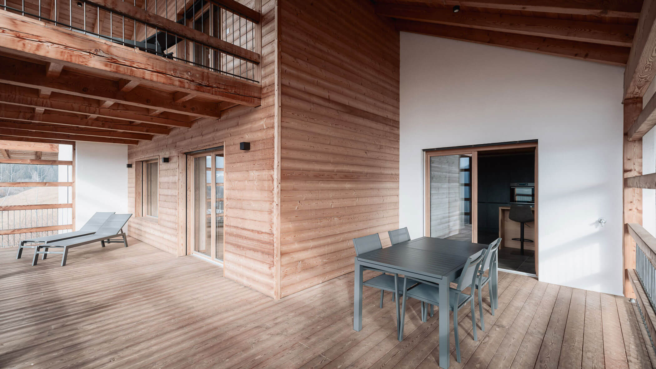Geräumige Holzterrasse mit Esstisch, Stühlen, Liegestühlen und großen Fenstern unter einem Holzdach. - Lantl Deluxe Apartments