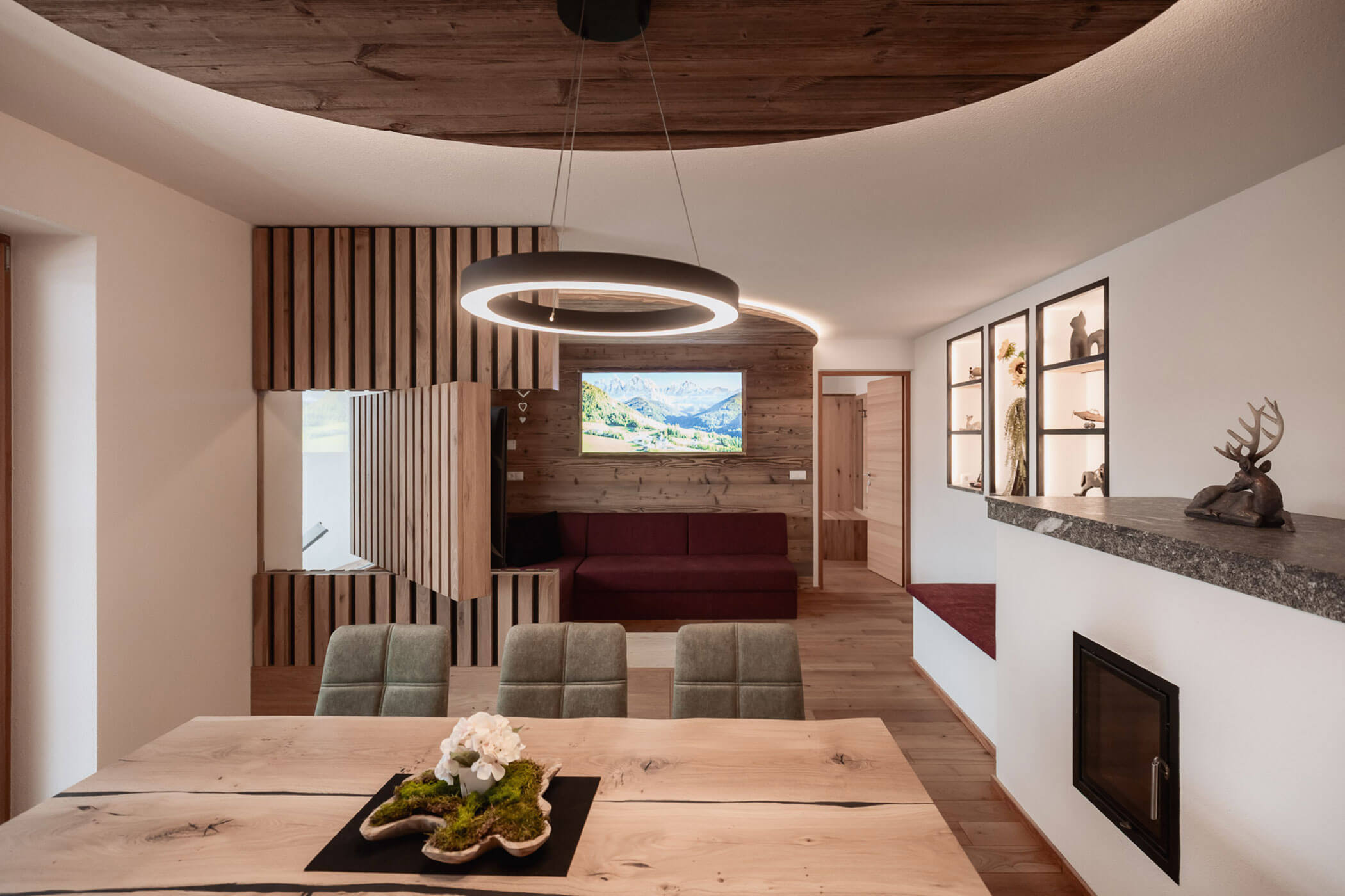 Modernes Wohnzimmer im alpinen Stil mit Holzakzenten, einer runden Leuchte, einem Kamin und einem Bergblick auf dem Fernseher. - Lantl Deluxe Apartments